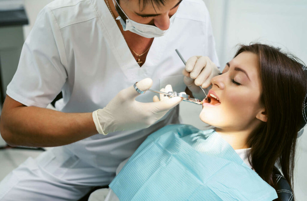 A male dentist administering anesthesia to a female patient's gum. before the dentist will do emergency tooth extraction that causes pain to the patient.
