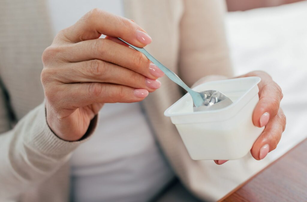 A close-up partial view of an adult woman eating frozen yogurt after a root canal.